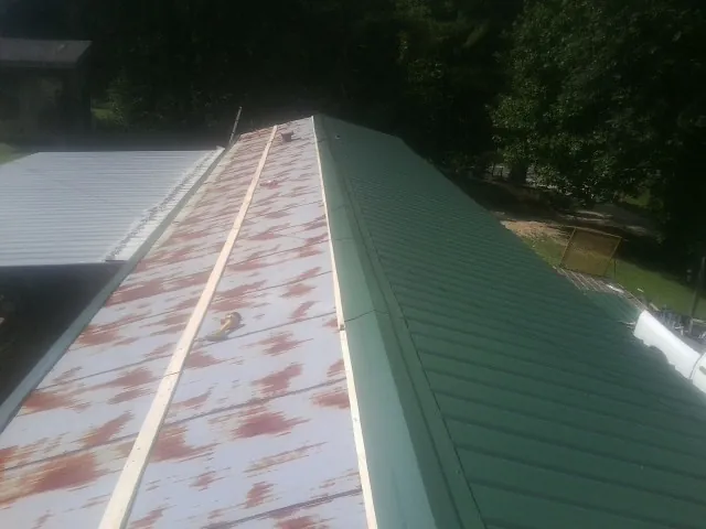 Old rusted panels beside newly installed green metal roofing — Wind Damage Roof Repair by Roofing Brothers in Colfax